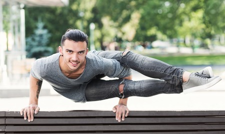 Man practicing advanced Crow yoga asana in urban area