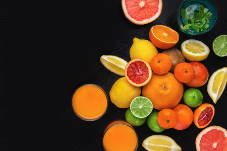 Citrus fruits with orange juice and lemonade on black background, top view, copy spaceの写真素材