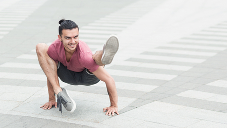 Sporty man doing advanced yoga asana outdoors on the street, copy spaceの写真素材