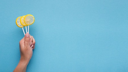 Fresh citrus lollipops in girls hand. Summer and fun concept, copy spaceの写真素材