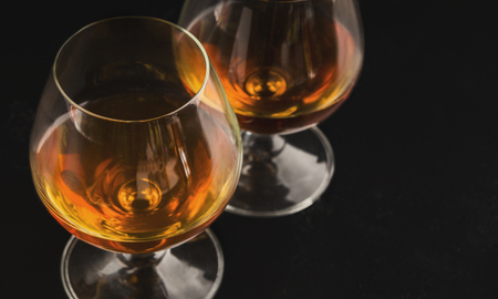 Elite alcoholic drink closeup. Two cognac portions in glass on black background, menu photo, copy...