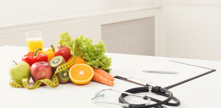 Nutritionist desk with healthy fruit and stethoscope. Dietitian workplace. Weight loss and right nutrition concept, copy spaceの写真素材