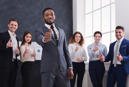 African-american businessman with team showing thumbs up in officeの写真素材
