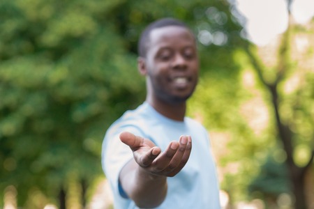 Follow me. Helping hand. Cheerful african-american man offering something, copy spaceの写真素材