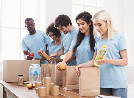 Group of multiethnic people packing goods for homeless in volunteer office, copy space