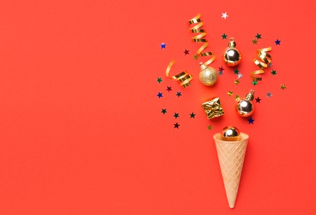 Ice cream cone with colorful christmas streamers on red backgroundの写真素材