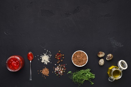 Healthy food preparation. Spices, sauces and herbs for salad dressing on black background, top view,...