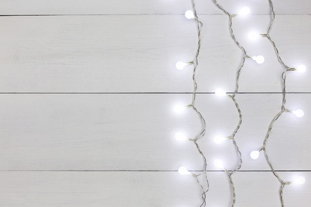 Border of christmas garland lights on white wooden backgroundの写真素材