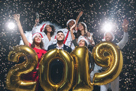 Office christmas party. Group of joyful colleagues having fun at new year celebration, holding...