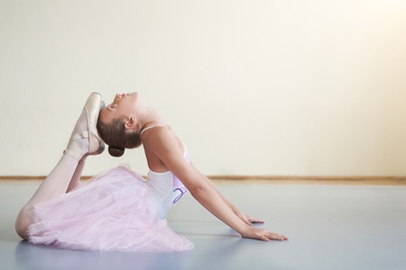 Little ballerina stretching before performance in ballet class, copy spaceの写真素材