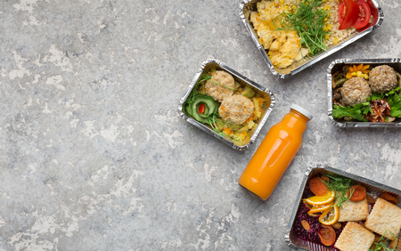Takeout food menu, assorted healthy meals in foil containers and orange smoothie, top view, copy spaceの写真素材