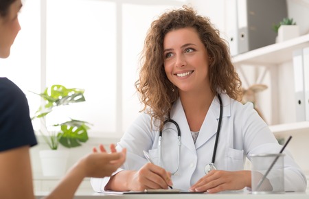 Healtcare and assistance concept. Doctor working in office and listening to patientの写真素材