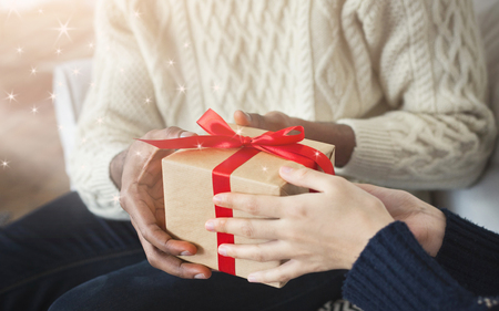Man giving her wife a gift at home while celebrating New Year, closeup