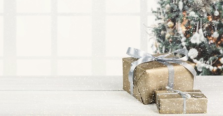Gift boxes at white wooden table and fir tree on background, copy space