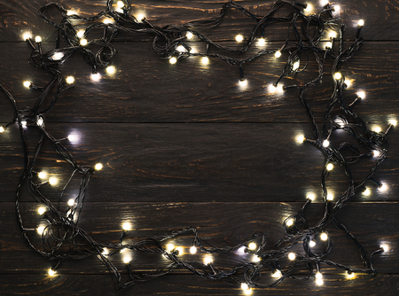 Frame of christmas garland lights on wooden rustic backgroundの写真素材