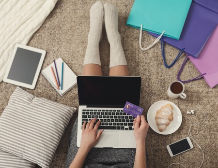 Fashion woman buying gifts online with laptop and credit card, with colorful shopping bags, top view, copy spaceの写真素材