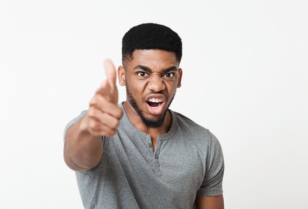 Angry furious african-american man screaming and pointing at camera, yelling and reprimanding
