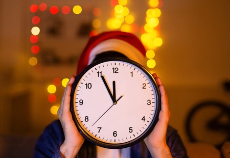 New year concept countdown. Man in santa hat showing clockの写真素材