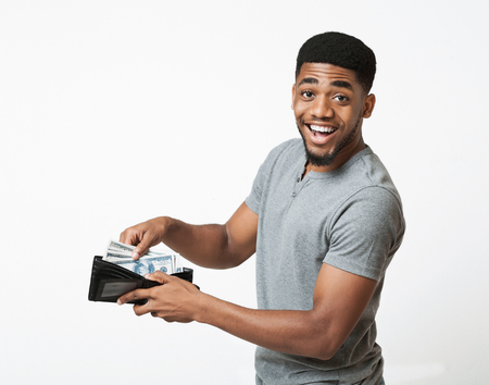 Finance, investment and money saving. Excited african-american man putting banknotes into wallet