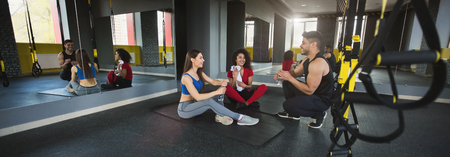 Having rest after workout. Diverse friends talking at gymの写真素材