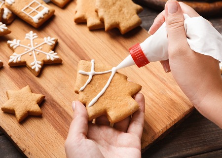 Confectioner decorating gingerbread with royal icing on cutting board, closeupの写真素材