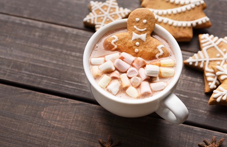 Gingerbread man in cup of hot cocoa and cookies on dark wooden table with copy spaceの写真素材