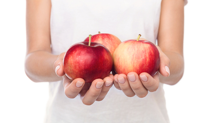 Three ripe red apples in female hands over white backgroundの写真素材