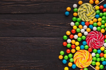 Assortment of colorful lollipops and candies on wooden background, copy spaceの写真素材