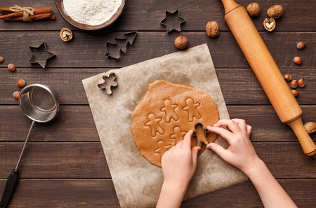 Making cookies. Child hands cutting gingerbread with metal cutters, top viewの写真素材