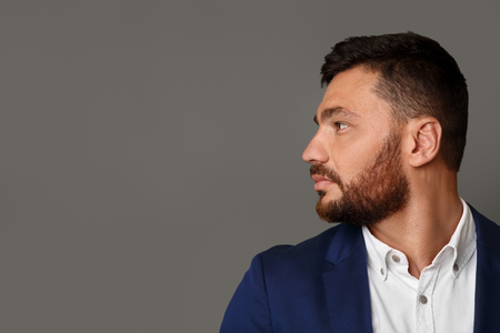 Side view portrait of thinking stylish young bearded businessman looking away at copy spaceの写真素材