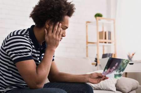 African-american teenager looking at photo of his girlfriend at home, copy spaceの写真素材