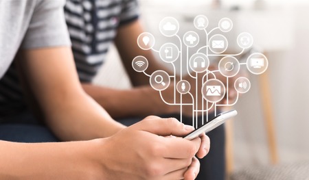 Young man using smartphone with virtual icons over screen