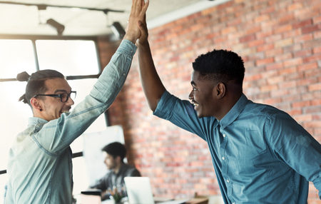 Happy diverse men giving high five, enjoying partnership in loft office, copy spaceの写真素材