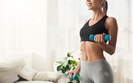 Sport training and healthy lifestyle. Woman exercising with dumbbells in hotel room during vacation, copy spaceの写真素材