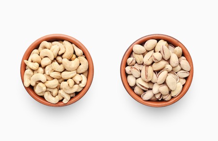 Bowls of cashew and pistachio nuts isolated on white background, top view