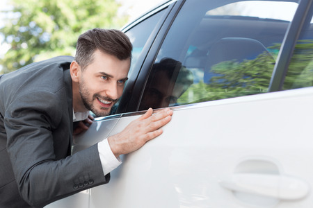 Car care. Business man obsessing about cleanliness of his new carの写真素材