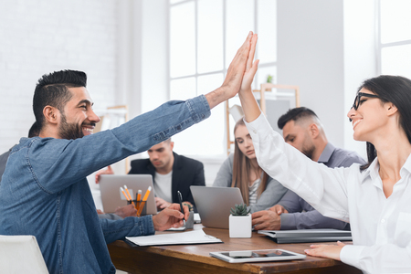 Business colleagues giving high-five, celebrating success at meetingの写真素材