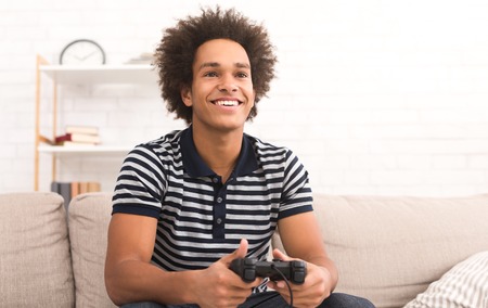 Guy playing football video game with joystick at homeの写真素材