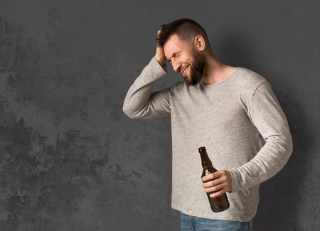 Man suffering from hangover with beer bottle, alcohol addiction and consequences concept, copy spaceの写真素材