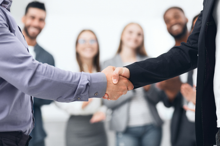 Finishing successful meeting. Young business people shaking hands in the officeの写真素材