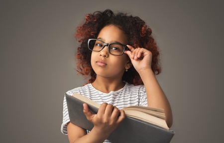 African little girl reading book at studio background