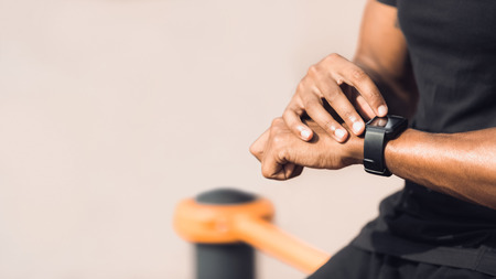 Man using black smart watch, checking heart rate after workout outdoors, copy spaceの写真素材