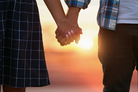 Couple in love holding hands while walking in city against sunsetの写真素材