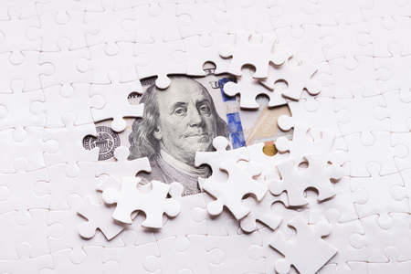 Hidden assets concept. One hundred dollar banknote appearing under puzzle piecesの写真素材