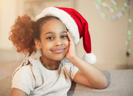 Little black girl in santa hat waiting for Christmasの写真素材