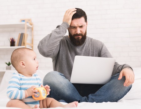 Business problem and paternity leave. Dad trying to work on laptop at home, while his baby son...