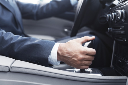 Businessman in suit changing gear in car, focus on handの写真素材