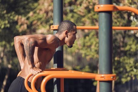 African-american man doing exercises on sports ground outdoors