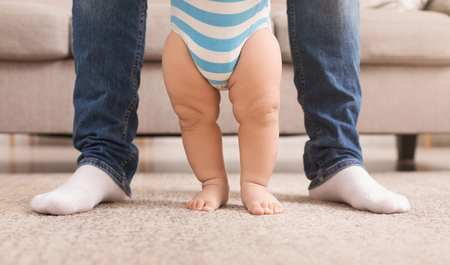 First step. Baby boy learning to walk with help of father, panoramaの写真素材