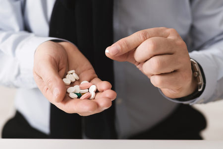 Senior man taking pills, holding heap of medicine, closeupの写真素材